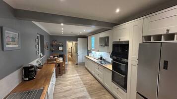 A modern kitchen with a wooden countertop, stainless steel appliances, and a view into the dining area.