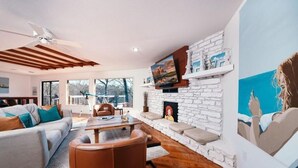 A modern living room with a fireplace, a sofa, a coffee table, and a TV mounted on a stone wall. - Winding Down at Lake Ann - Stunning Views Await! (Bella Vista)