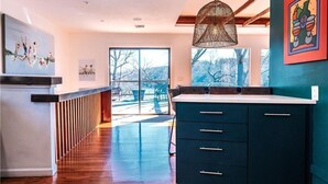A modern kitchen with dark cabinetry, a hanging light fixture, and artwork on the walls. - Winding Down at Lake Ann - Stunning Views Await! (Bella Vista)
