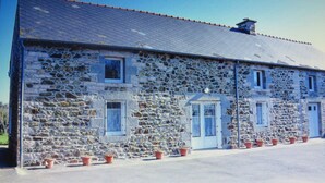 A stone building with a tiled roof, multiple windows, and doors. There are potted plants in front of the building. - For rent, single-storey farmhouse with large grounds. not enclosed (Lamballe-Armor)