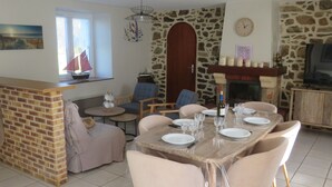 A dining area with a stone wall, a fireplace, and a television. - For rent, single-storey farmhouse with large grounds. not enclosed (Lamballe-Armor)