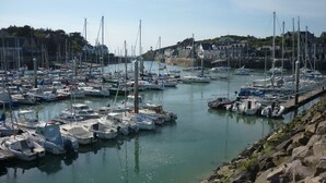 A marina with numerous boats docked, surrounded by buildings and a rocky shoreline. - For rent, single-storey farmhouse with large grounds. not enclosed (Lamballe-Armor)