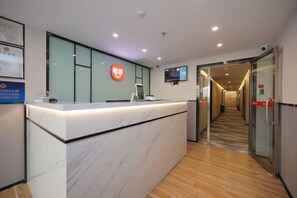 A reception desk with a digital screen, a glass partition, and a corridor leading to a door. - Jitai Hotel (Beijing Tongren Hospital Zhanqian Square) (Beijing)