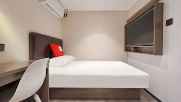 A compact hotel room with a single bed, a desk, a chair, and a large window.