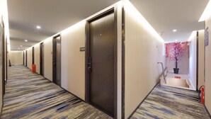 A hotel corridor with multiple doors, a patterned carpet, and a staircase leading to an upper level. - Jitai Hotel (Beijing Tongren Hospital Zhanqian Square) (Beijing)