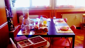 A dining area with a table set for breakfast, including plates, cups, and a fruit bowl. - Pirelliguesthouselakeofcomo (Varenna)