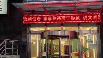 A hotel entrance with a revolving door and a neon sign above.