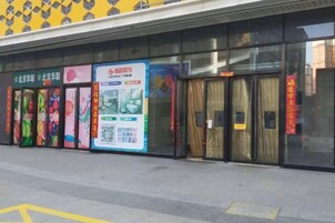 Fachada de edificio con amplios ventanales, un toldo amarillo estampado y varios carteles de colores.