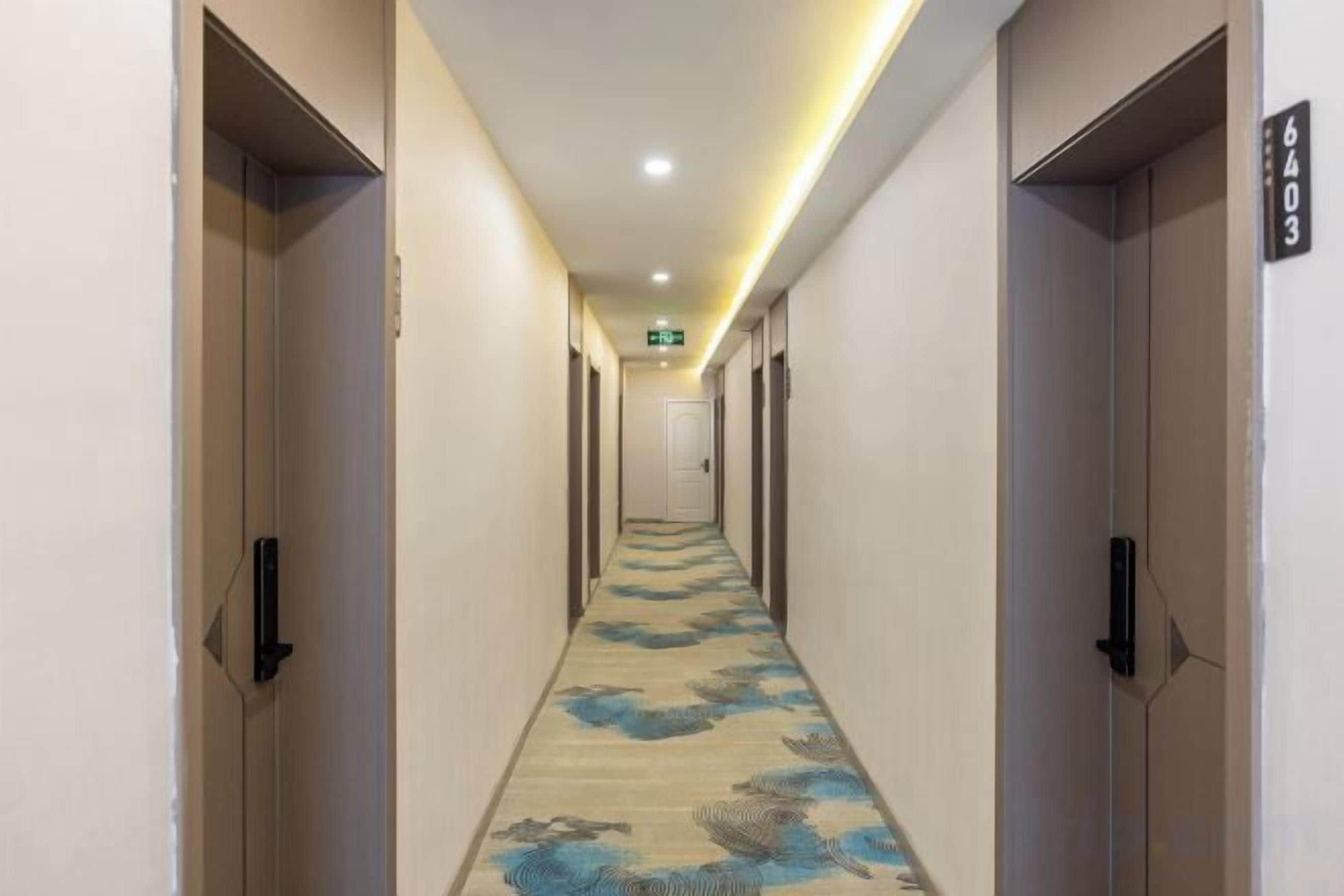 A hotel hallway with doors on both sides, a carpet with a floral pattern, and a sign indicating room number 6403.