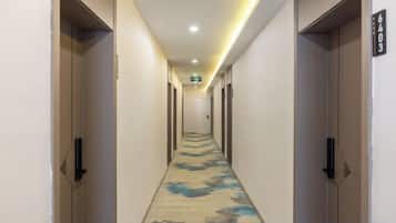 A hotel hallway with doors on both sides, a carpet with a floral pattern, and a sign indicating room number 6403.