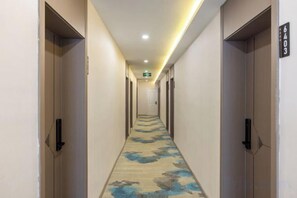 A hotel hallway with doors on both sides, a carpet with a floral pattern, and a sign indicating room number 6403. - Jinxin Hotel (Xining)