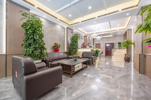 A modern lobby with leather sofas, a reception desk, and potted plants. - Jinxin Hotel (Xining)