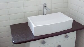 A bathroom with a white sink, dark countertop, and white cabinets.