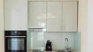 A compact kitchen with a built-in oven, a coffee maker, and a sink.