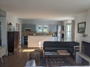 A modern kitchen with a central island, a dining area with a sofa and ottomans, and a fireplace. - Family home in Loix, with a large, private, enclosed garden, a 2-minute bike ride from the village (Loix)