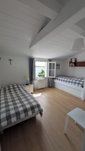 A room with two beds, a window, a radiator, a lamp, and a shelf with books. - Family home in Loix, with a large, private, enclosed garden, a 2-minute bike ride from the village (Loix)
