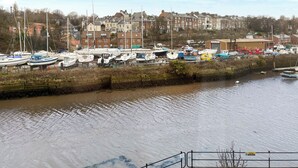 A marina with boats docked, a brick wall, and residential buildings in the background. - 3 bedroom accommodation in Whitby (Whitby)