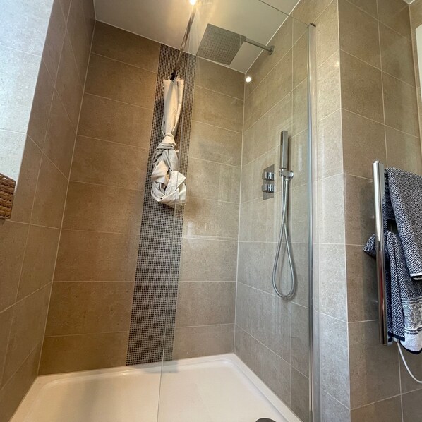 A modern bathroom with a shower, a bathtub, and a towel rack.
