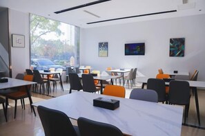 Un comedor moderno con mesas, sillas, ventanas amplias y obras de arte en las paredes.