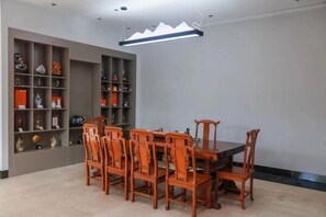 A dining area with a wooden table and chairs, surrounded by shelves with various items. - Holiday Inn Hebi Xianhe Lake (Qibin Avenue Municipal Government Branch) (Hebi)