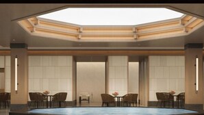 Amplio espacio interior con piscina central, rodeado de zonas de estar y un techo alto con tragaluces.