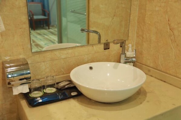 A bathroom with a white sink, a mirror, and a towel dispenser. - Holiday Inn Hebi Xianhe Lake (Qibin Avenue Municipal Government Branch) (Hebi)