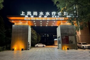 A hotel entrance with a sign in Chinese characters, a paved driveway, and two parked cars. - Holiday Inn Hebi Xianhe Lake (Qibin Avenue Municipal Government Branch) (Hebi)
