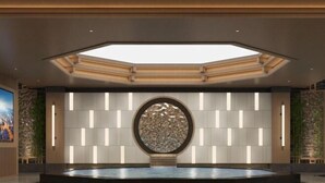 Un vestíbulo espacioso con una fuente circular central, iluminación empotrada y un tragaluz.