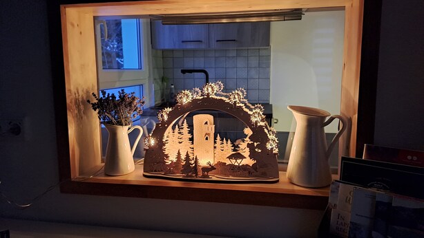 Una cocina con encimera de madera, un marco de ventana decorativo y un florero con flores secas.