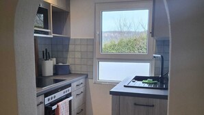 Una cocina compacta con horno integrado, microondas y ventana que proporciona luz natural.
