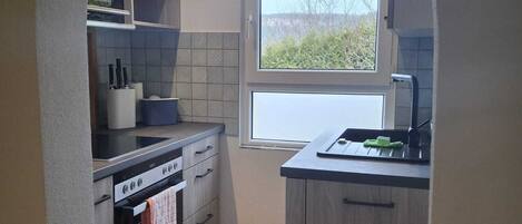 A compact kitchen with a built-in oven, microwave, and a window providing natural light.