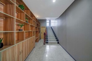 A hallway with wooden shelving units, a staircase, and a door at the end. - Shangjie Fashion Hotel (Shanghai)