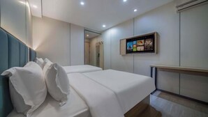 Una habitación de hotel moderna con una cama, un televisor de pantalla plana en la pared y un banco de madera.