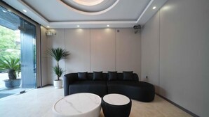 Una sala de estar moderna con un sofá modular, dos mesas de centro redondas y una planta en maceta.