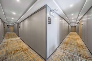 A hotel corridor with a patterned carpet, a security camera, and a sign indicating a room number. - Shangjie Fashion Hotel (Shanghai)