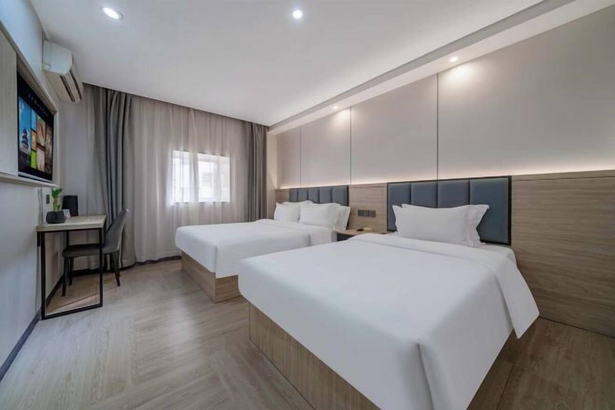 Une chambre d’hôtel avec deux lits, un bureau et une télévision.