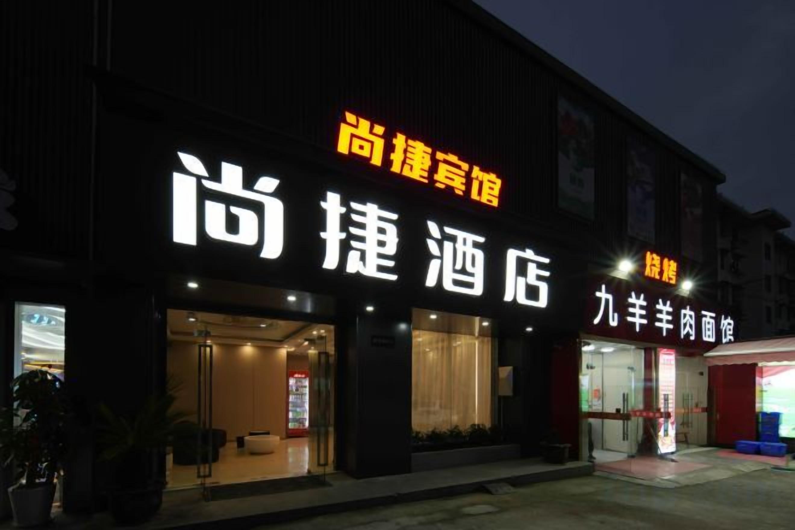 A hotel with a prominent sign, a visible entrance, and a small outdoor seating area.