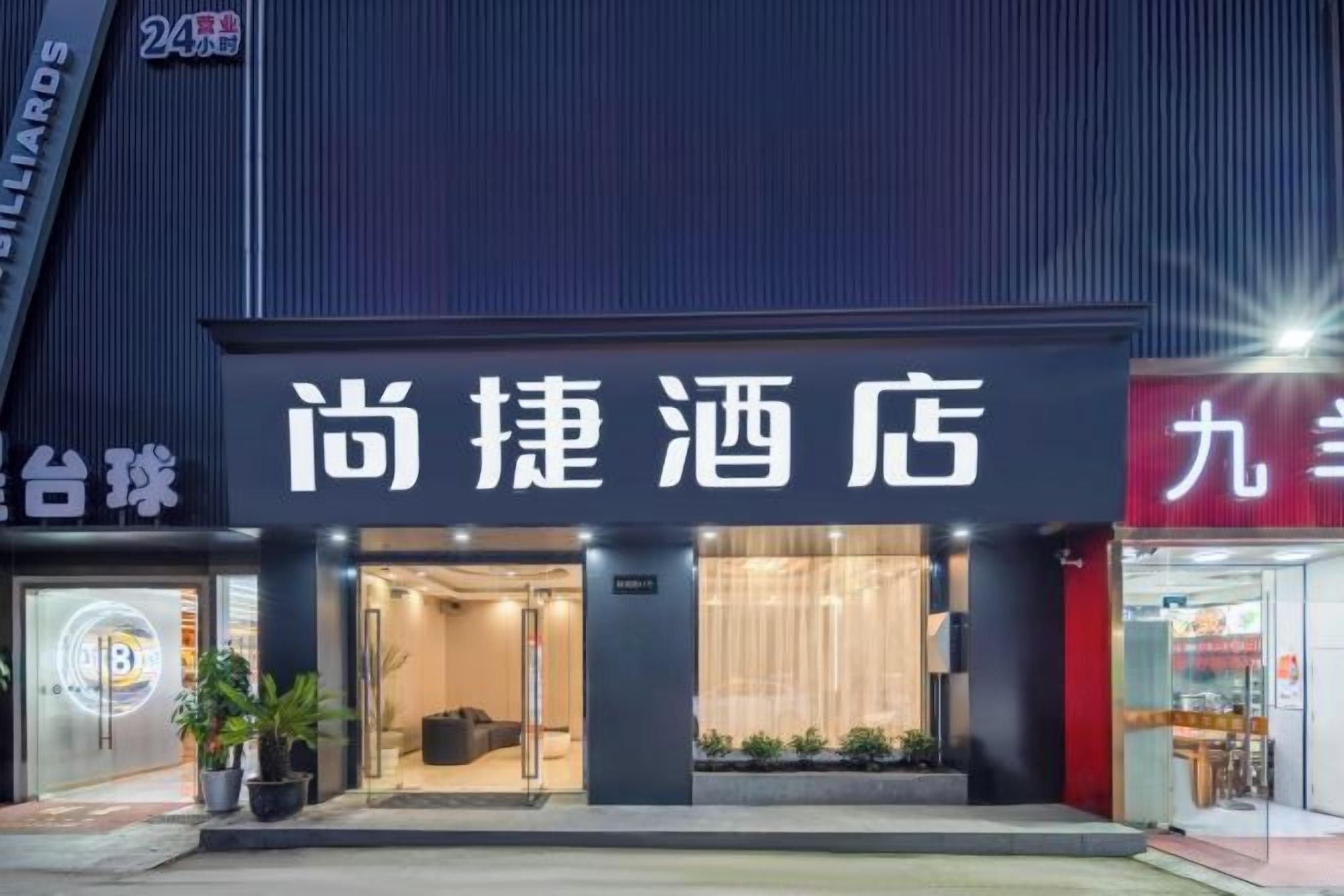 A hotel entrance with a signboard, a reception area, and a visible entrance door.