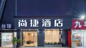 A hotel entrance with a signboard, a reception area, and a visible entrance door.