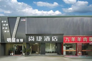 Un hotel con fachada moderna, una entrada destacada y señalización para un restaurante.
