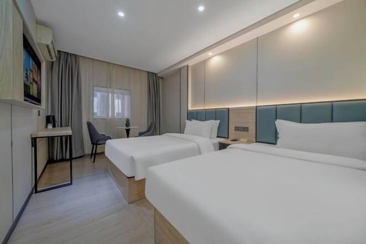 Une chambre d’hôtel avec deux lits, un bureau, une chaise et un téléviseur.