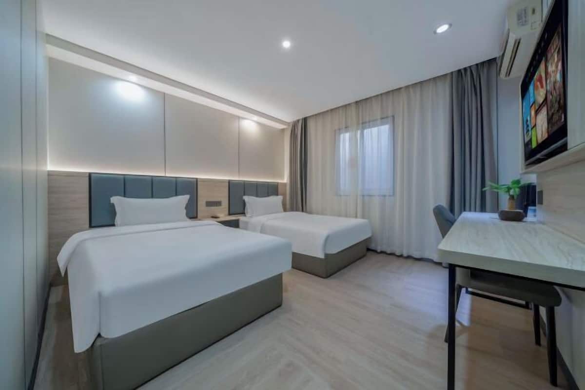 Une chambre d’hôtel avec deux lits, une table à manger, un téléviseur et une fenêtre avec des rideaux.