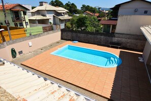 Piscina al terrat amb vista a cases properes i un cel serè.