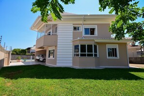 Un edificio residenziale a due piani con un balcone, un garage e un prato curato.