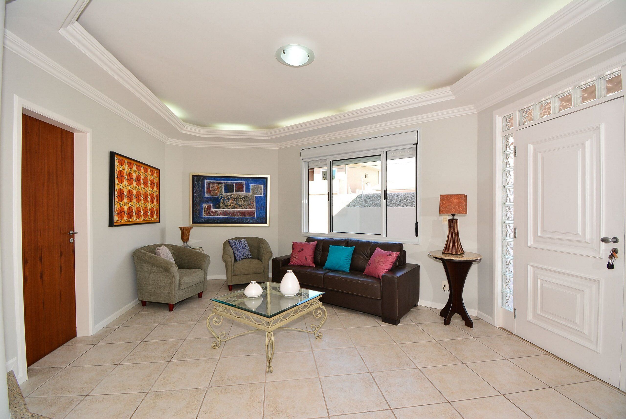 A living room with a brown sofa, a green armchair, and a glass coffee table.