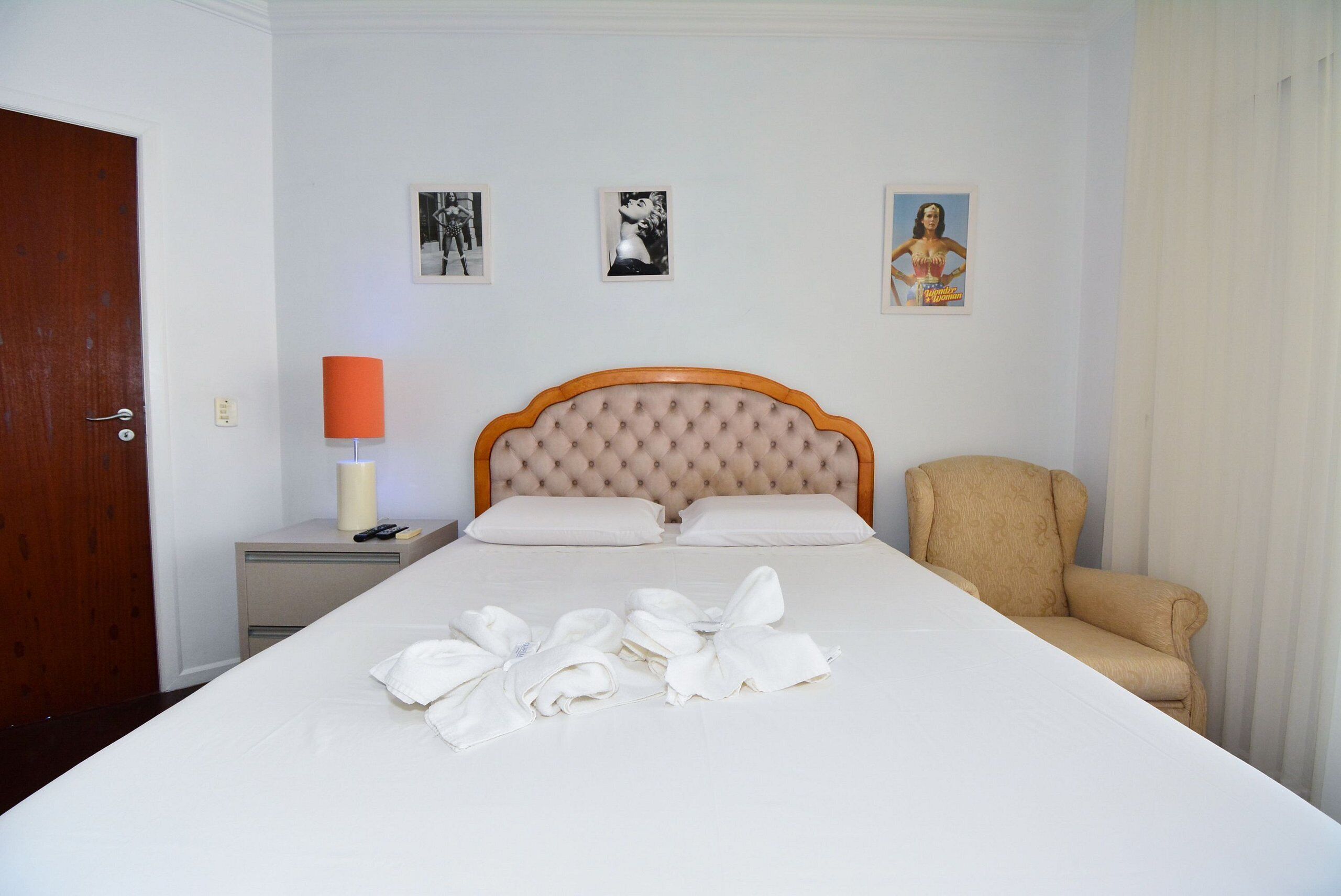 A neatly made bed with towels, a nightstand with a lamp, and a chair.