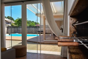A modern kitchen with a large window, a pool, and a view of the surrounding area. - Casa com Piscina Morro das Pedras (Florianopolis)