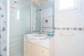 Een badkamer met een witte wastafel, een spiegel en een douche.