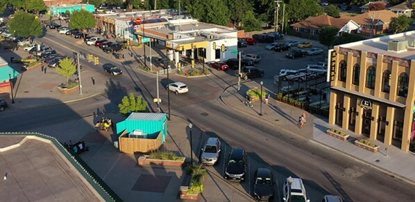 A street view with a gas station, parked cars, and buildings.