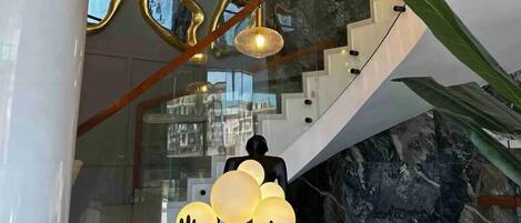 A modern interior with a curved staircase, a glass railing, and a decorative light fixture.